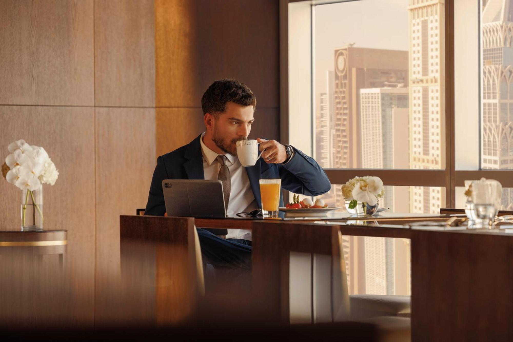 Jumeirah Emirates Towers Dubai Exterior photo A man drinking coffee
